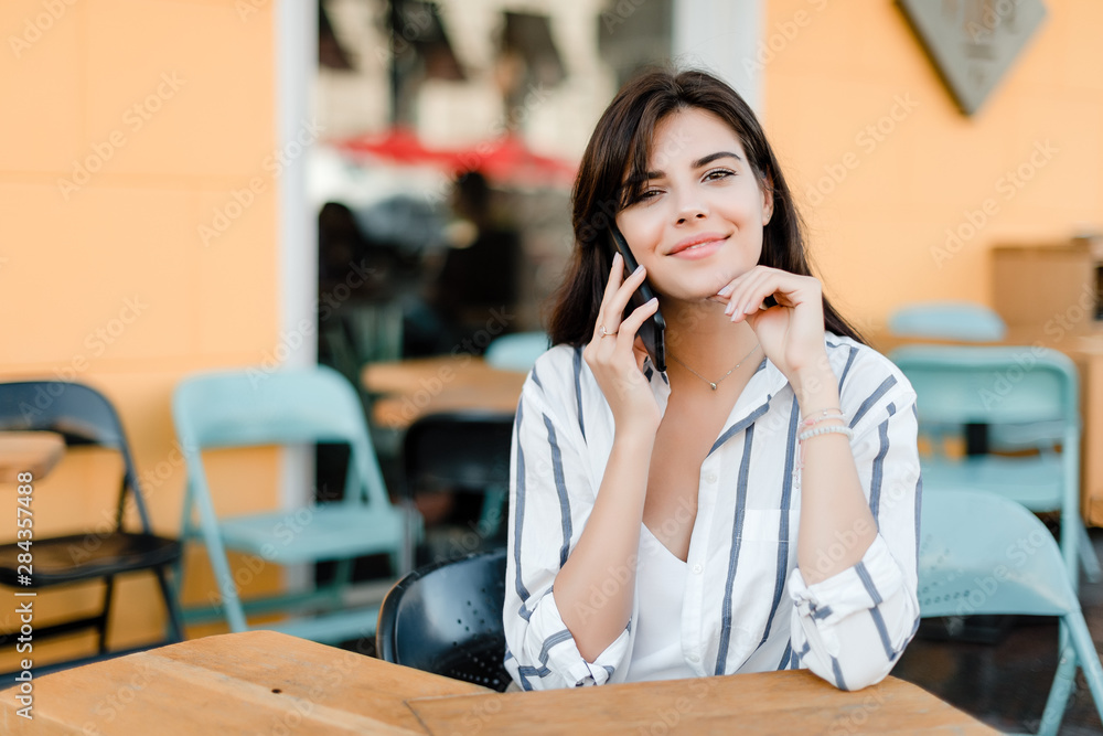 woman uses phone sitting in cafe outdoors woman uses phone sitting in cafe outdoors