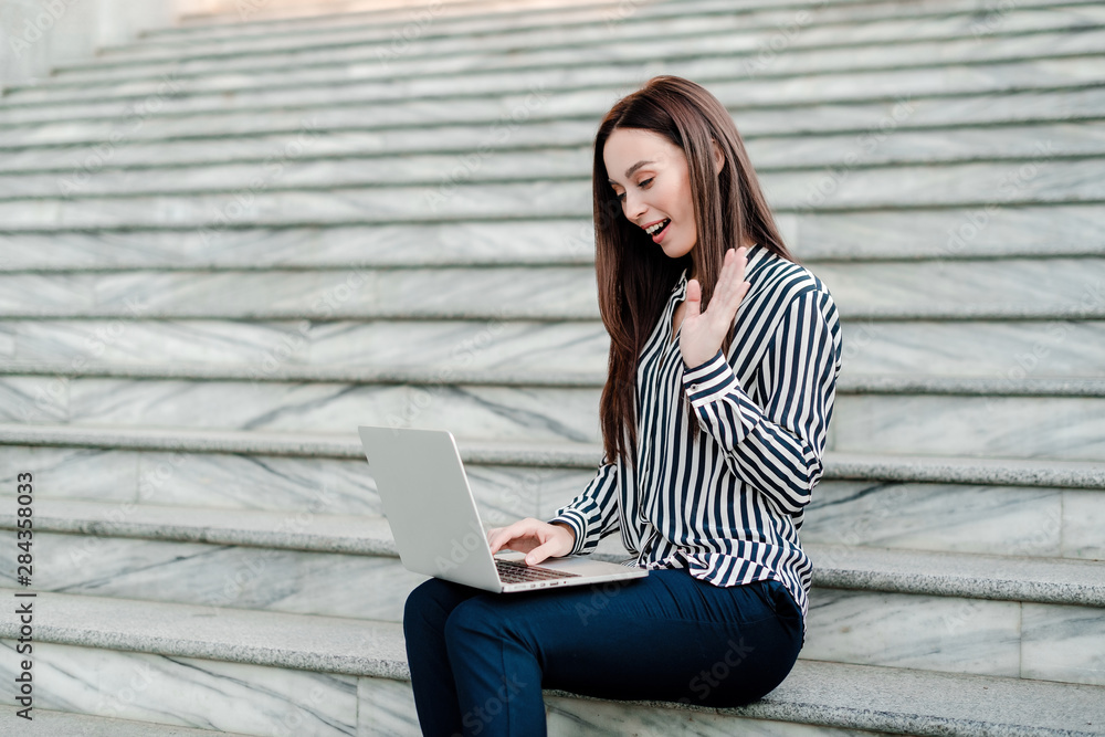 pretty woman smiling and wawing her hand to the laptop pretty woman smiling and wawing her hand to the laptop