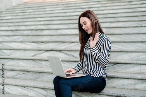 pretty woman smiling and wawing her hand to the laptop