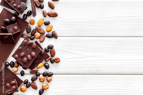 Chocolate bars and nuts on white wooden table background top view mockup