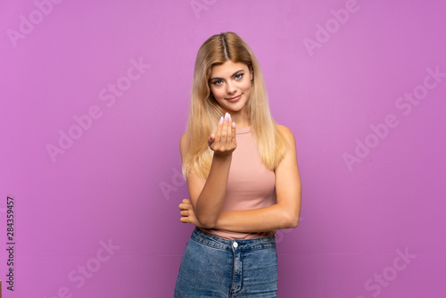Teenager girl over isolated purple background inviting to come with hand. Happy that you came © luismolinero