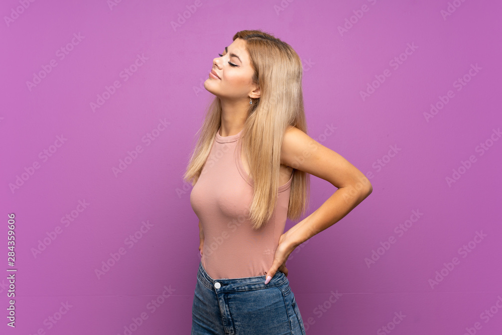 Teenager girl over isolated purple background suffering from backache for having made an effort Teenager girl over isolated purple background suffering from backache for having made an effort