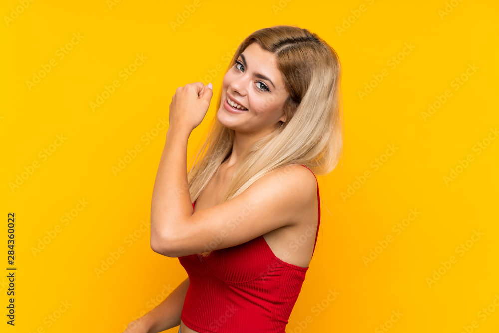 Teenager girl over isolated yellow background celebrating a victory