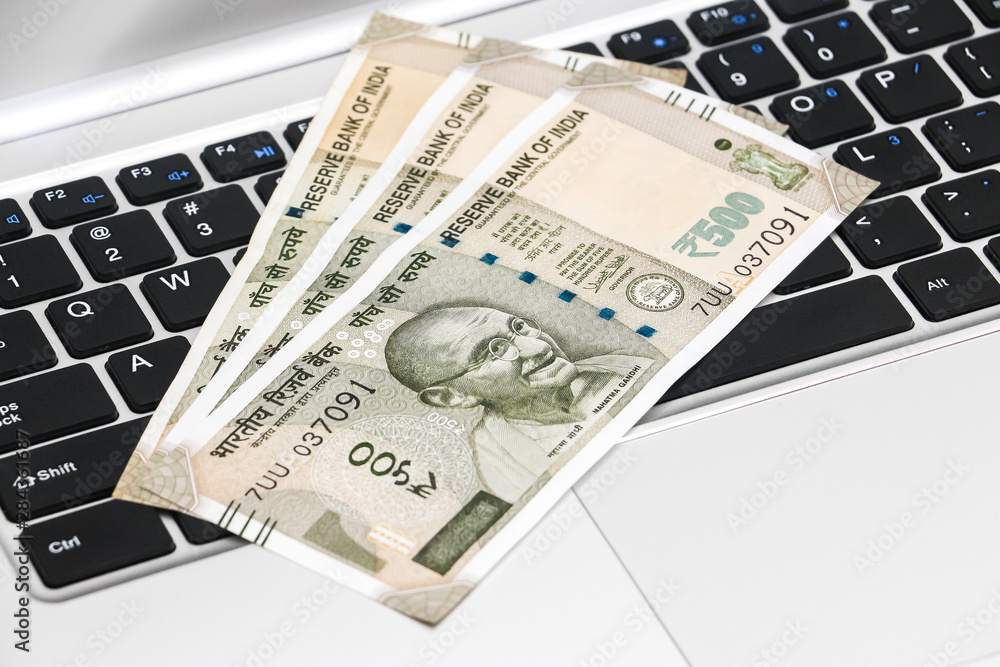 Close up view of brand new indian 500 rupees banknotes and laptop. Close up view of brand new indian 500 rupees banknotes and laptop.