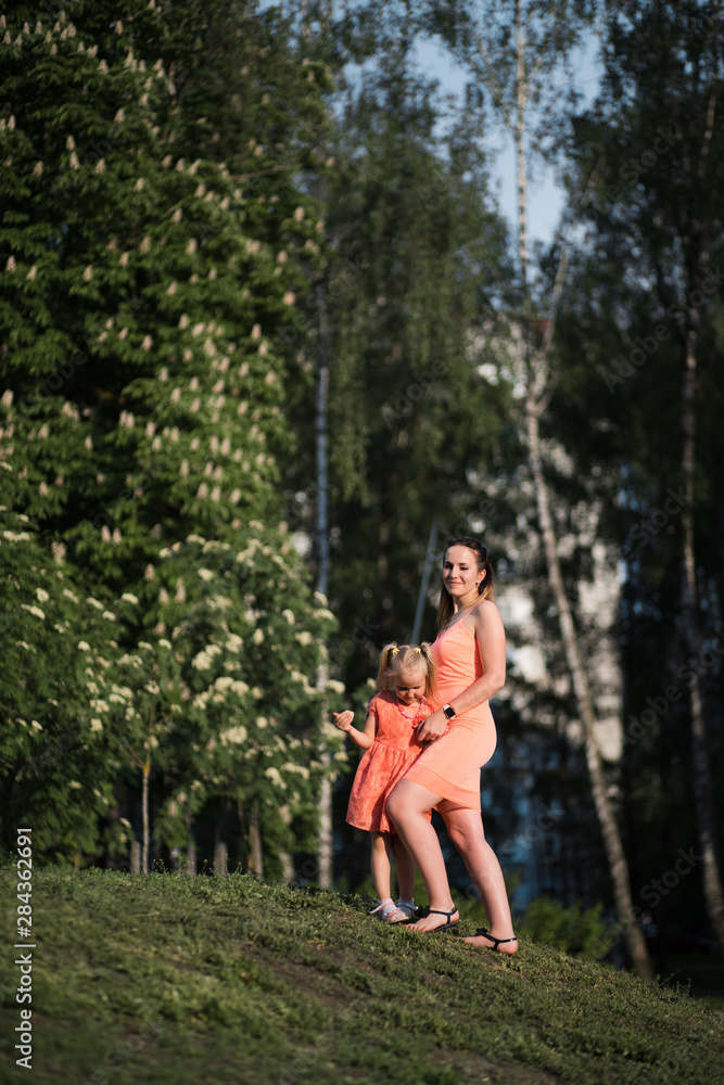 Happy mother playing with her little baby girl daughter and having fun - Young caucasian white mom wearing summer bright vivid color dress - Happinness family concept