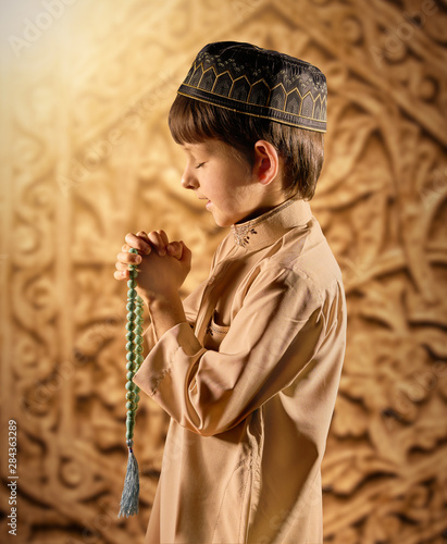 Canvas Print Little muslim boy with rosary beads praying to God