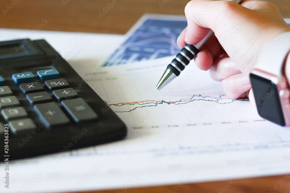 Woman Writing at a Business Desk with Graphs and Charts Woman Writing at a Business Desk with Graphs and Charts