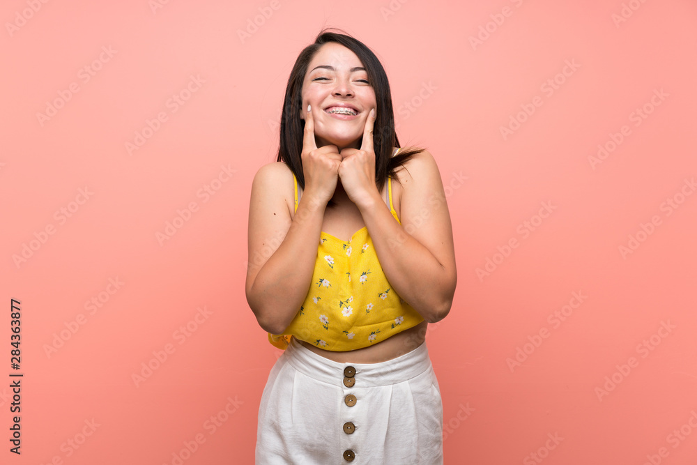 Young Mexican woman over isolated wall smiling with a happy and pleasant expression Young Mexican woman over isolated wall smiling with a happy and pleasant expression