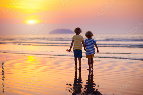 Child playing on ocean beach. Kid at sunset sea.