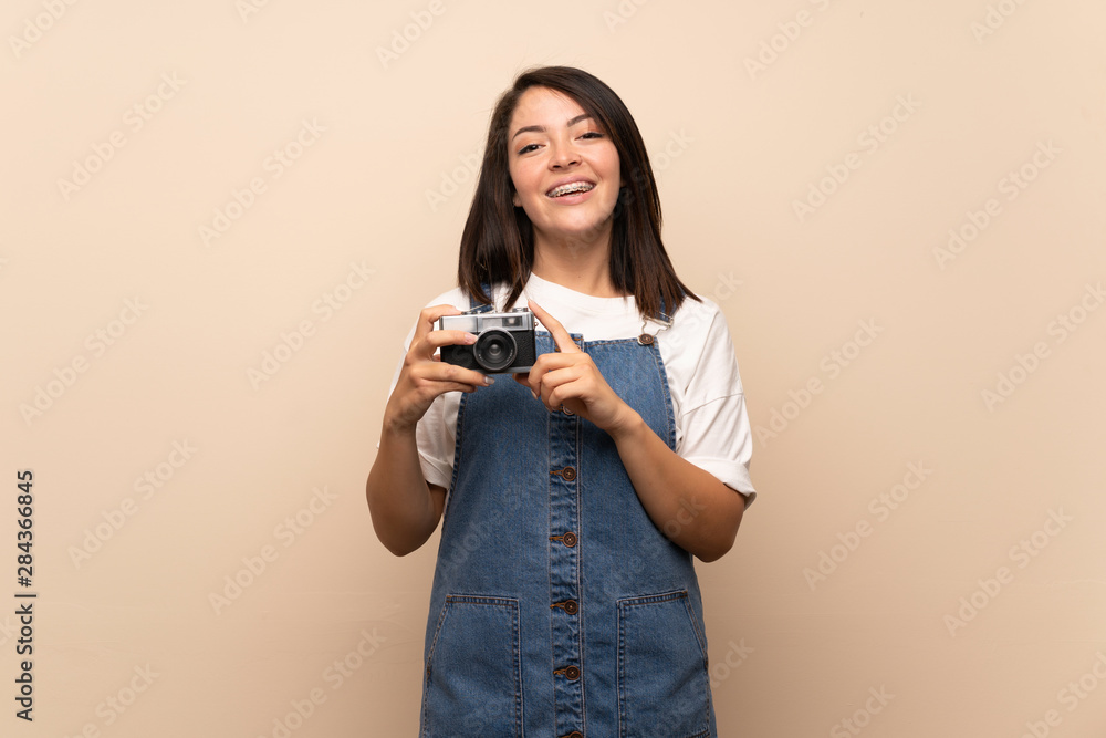 Young Mexican woman over isolated background holding a camera Young Mexican woman over isolated background holding a camera