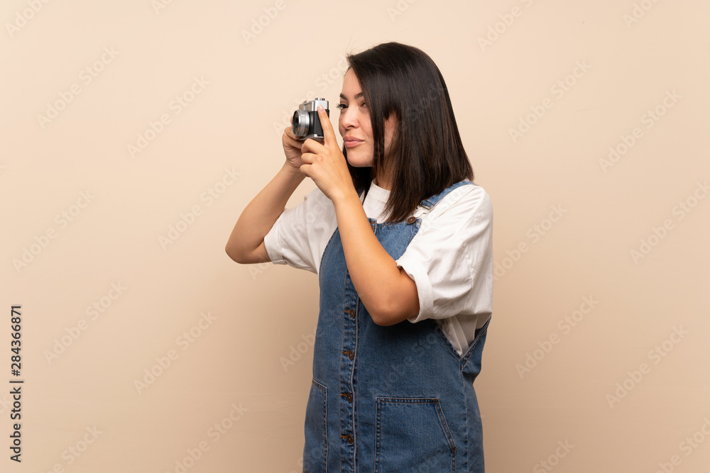Obraz premium Young Mexican woman over isolated background holding a camera