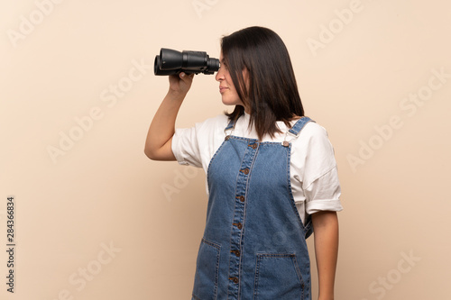 Young Mexican woman over isolated background with black binoculars © luismolinero