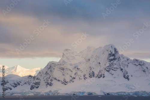 Antarctica. Paradise Harbor. Snowy mountains and clouds at sunrise.