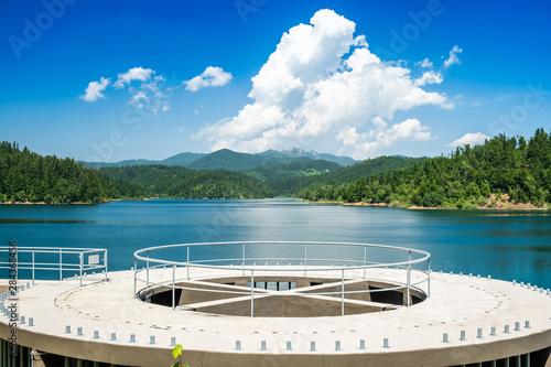 Hydro power plant concrete structure on beautiful blue lake in Gorski kotar, Lokve, Croatia, with Risnjak mountain in background, reflection in water photo
