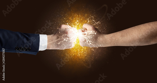 Two hands fighting with orange dust, spark, glow and smoke concept