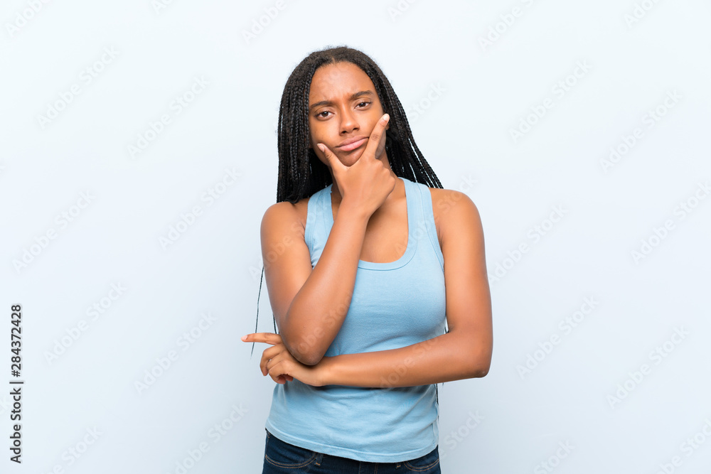 African American teenager girl with long braided hair over isolated blue background thinking an idea African American teenager girl with long braided hair over isolated blue background thinking an idea