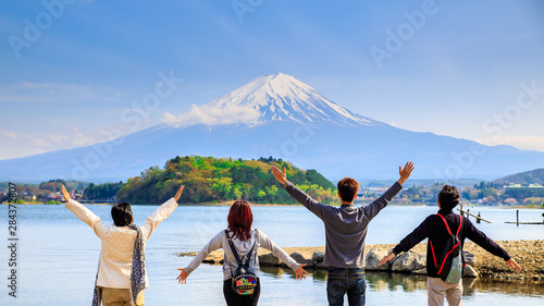 Mt diamond fuji with snow and flower garden along the lake walkway at Kawaguchiko lake in japan, Mt Fuji is one of famous place in Japan. People hands up and looking far away.