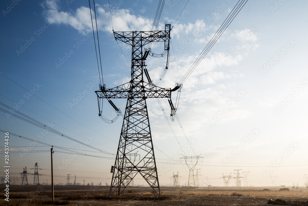 Fototapeta premium China, Shanxi Province, Datong, High Tension Power Pylons and electrical lines leading from coal-fired Datong No. 2 Power Station at dawn