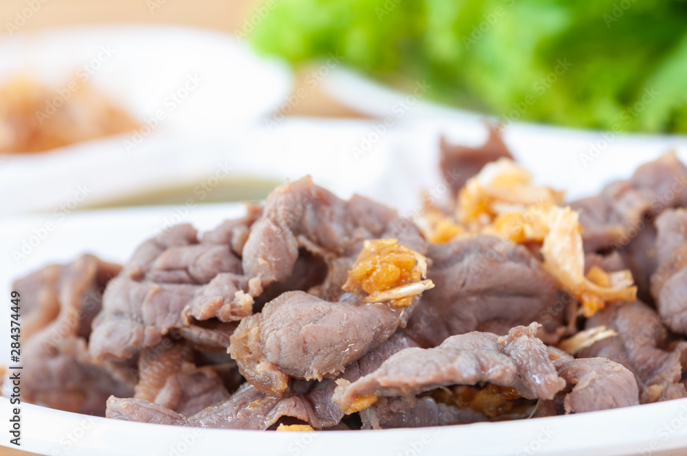 Fresh scalded meat serve with deep fried garlic and spicy sauce in white plate. Fresh scalded meat serve with deep fried garlic and spicy sauce in white plate.