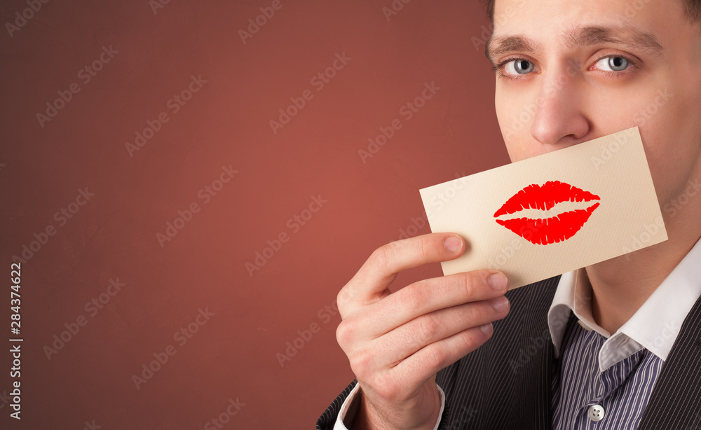 Person smiling with a card on the front of his mouth with a red lips on it Person smiling with a card on the front of his mouth with a red lips on it