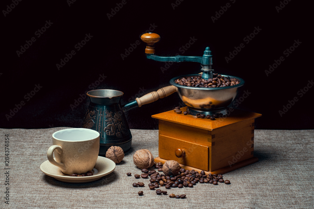 coffee cup with a cezve and coffee grinder with coffee beans and nuts on a dark background coffee cup with a cezve and coffee grinder with coffee beans and nuts on a dark background