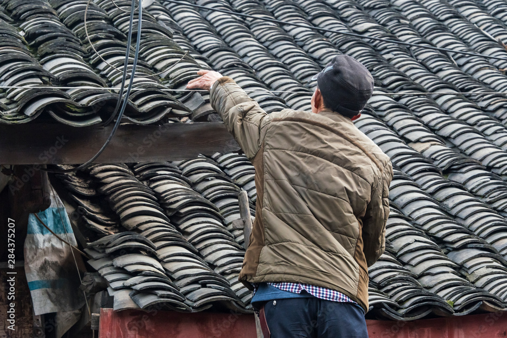 Fototapeta premium Repairing tiled roof of a traditional house, Pengzhen, Chengdu, Sichuan Province, China