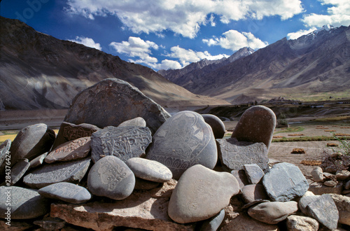 Asia, India, Ladakh, Zanskar Valley. Mani stones, with their smooth sides and carved prayers, contrast with the jagged peaks around Zanskar Valley, India. © Ric Ergenbright/Danita Delimont