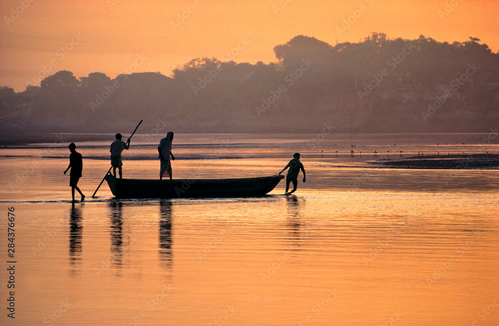 Asia, India, Agra. At dawn, men struggle to pull their boat across the shallow Jumna River in Agra, India. Asia, India, Agra. At dawn, men struggle to pull their boat across the shallow Jumna River in Agra, India.