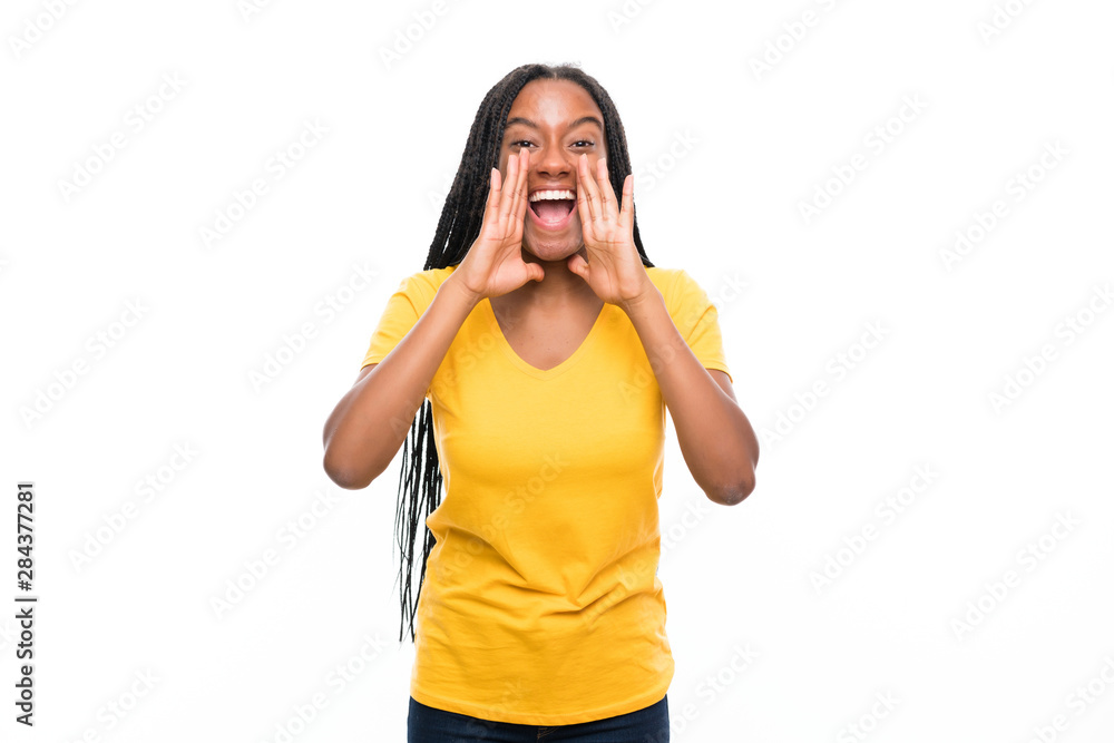 African American teenager girl with long braided hair over isolated white background shouting with mouth wide open African American teenager girl with long braided hair over isolated white background shouting with mouth wide open