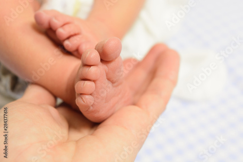 Newborn baby feet in man hand with blue background