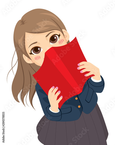 Cute shy student girl hiding behind red textbook