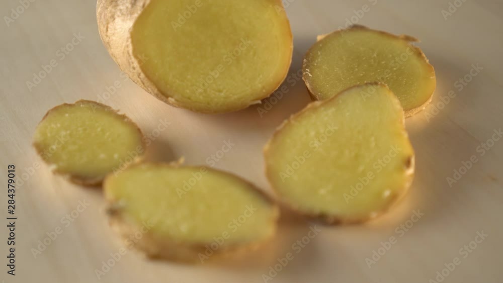 Juicy ripe slices of ginger root spin on a wooden surface. Cooking natural healthy foods for healing Juicy ripe slices of ginger root spin on a wooden surface. Cooking natural healthy foods for healing