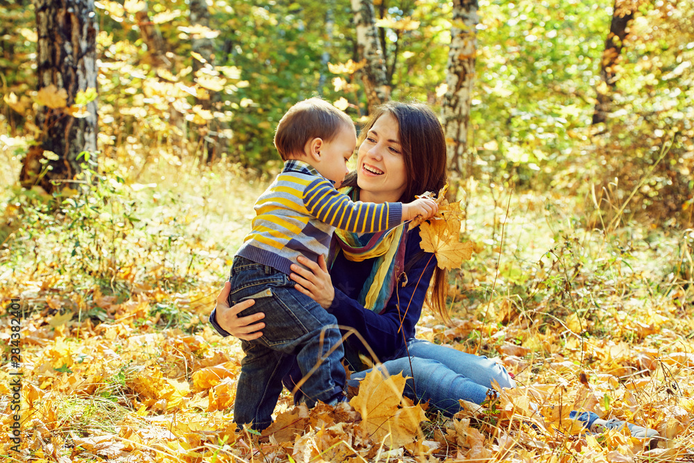 outdoor portrait of a young mother with her baby. Mom and son in an autumn park.