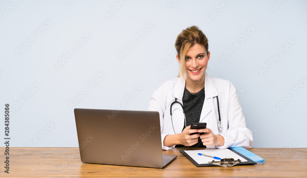 Blonde doctor woman sending a message with the mobile Blonde doctor woman sending a message with the mobile