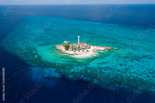 Aerial drone view of tropical Capitancillo Island in the Philippines showing its lighthouse and coral reef © whitcomberd
