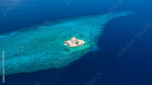 Aerial drone view of tropical Capitancillo Island in the Philippines showing its lighthouse and coral reef