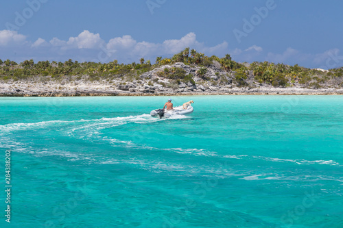 Bahamas, Exuma Island, Cays Land and Sea Park. Man and dog in skiff. Credit as: Don Paulson / Jaynes Gallery / DanitaDelimont.com