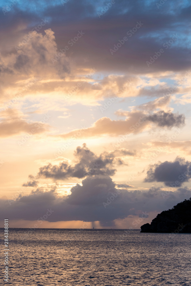 UK, British Virgin Islands. Sailboat and rain on horizon at sunset