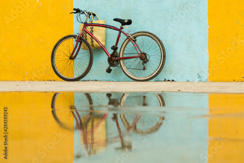 Cuba, Trinidad. Bicycle and reflection against yellow and blue walls.