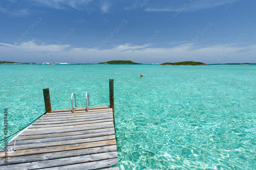 Dock in the foreground, clear water and blue sky in the background, taken on Staniel Cay, Exuma, Bahamas