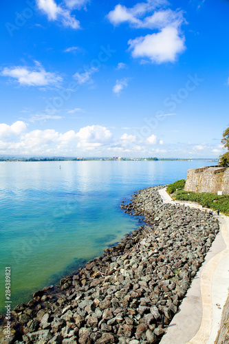 San Juan  Puerto Rico - A sidewalk passes above a rocky beach of calm water.
