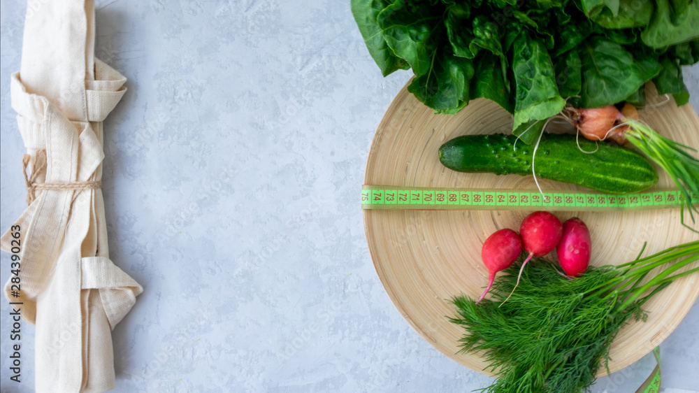 Cotton bag fitness salad, cucumber, radish, dill and centimeter on bamboo plate. The concept of ecology and healthy food, diet and weight loss.