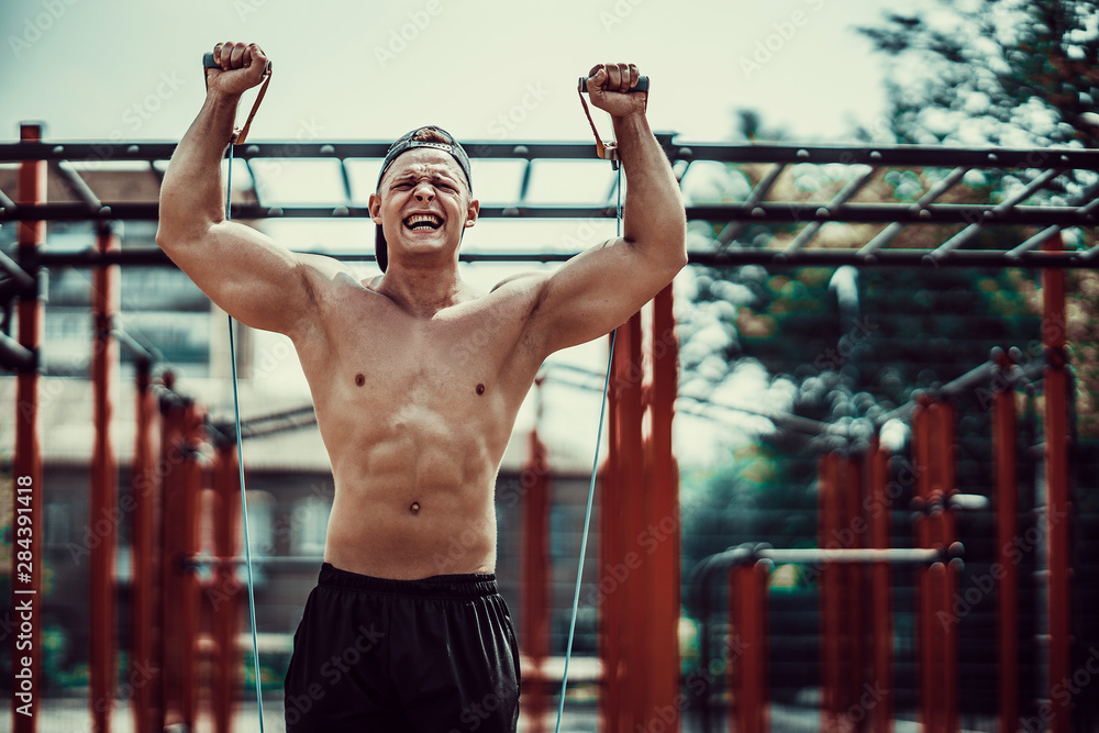 Fitness man exercising with stretching band. Muscular sports man exercising with elastic rubber band. Guy working out with rubber band. Fit, fitness, exercise, workout and healthy lifestyle Fitness man exercising with stretching band. Muscular sports man exercising with elastic rubber band. Guy working out with rubber band. Fit, fitness, exercise, workout and healthy lifestyle