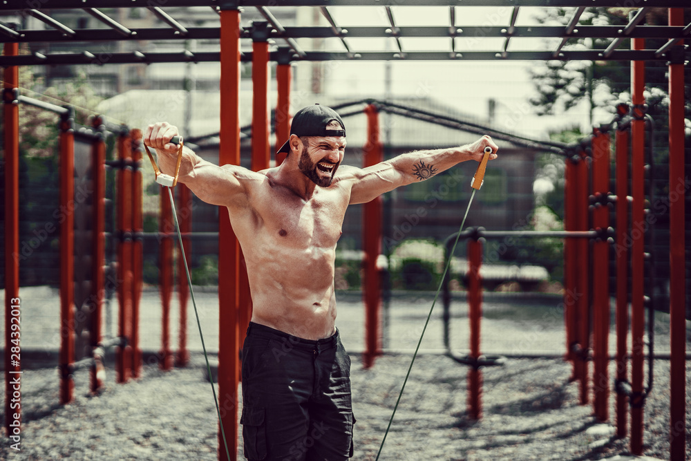 Fitness man exercising with stretching band. Muscular sports man exercising with elastic rubber band. Guy working out with rubber band. Fit, fitness, exercise, workout and healthy lifestyle Fitness man exercising with stretching band. Muscular sports man exercising with elastic rubber band. Guy working out with rubber band. Fit, fitness, exercise, workout and healthy lifestyle