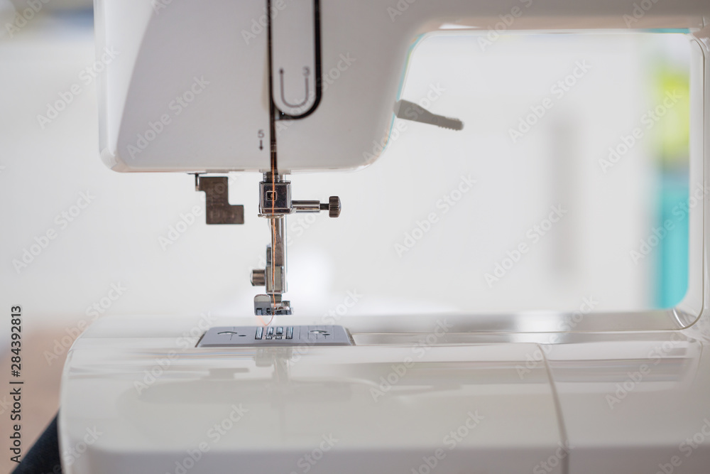 sewing machine with colour thread and needle on a table with blurred background, Tailor's work table, textile or fine cloth making, industrial fabric, home appliances tool.