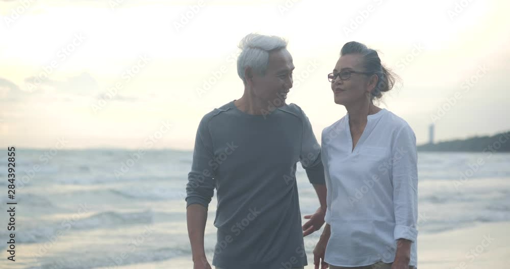 Asian senior couple walking and talking on beautiful tropical beach in ...
