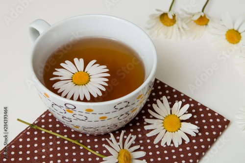 cup of tea on brown polka dot fabric with camomile on a white background