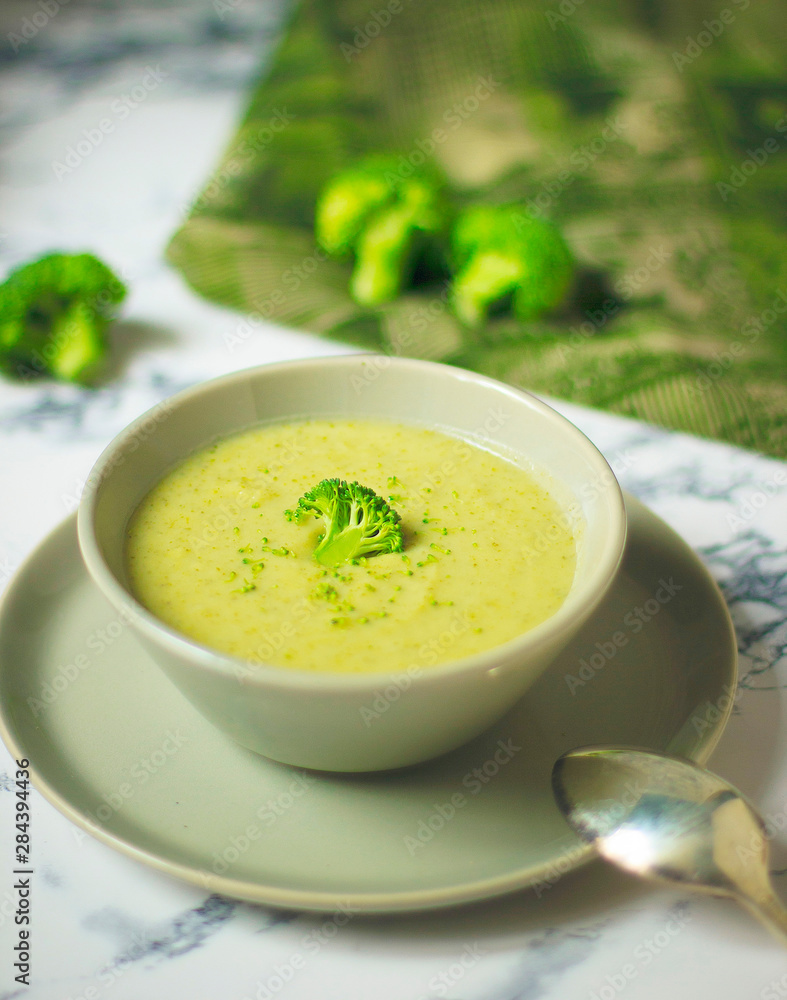 Fresh Broccoli cream soup on two gray ceramic bowl on plate with spoon on marble background,vegetarian food,healthy concept Fresh Broccoli cream soup on two gray ceramic bowl on plate with spoon on marble background,vegetarian food,healthy concept