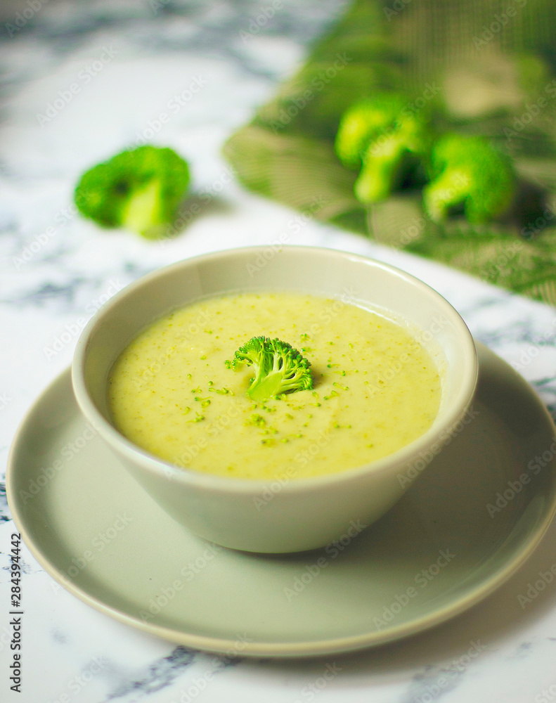 Fresh Broccoli cream soup on two gray ceramic bowl on plate with spoon on marble background,vegetarian food,healthy concept Fresh Broccoli cream soup on two gray ceramic bowl on plate with spoon on marble background,vegetarian food,healthy concept