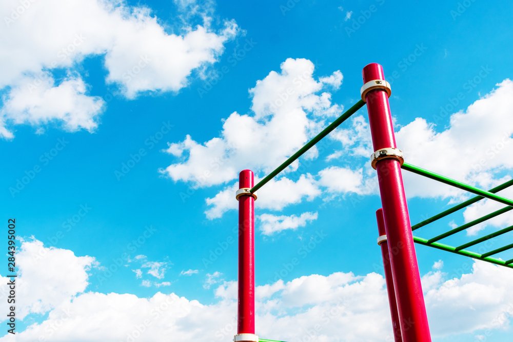 Horizontal bars against a blue cloudy sky in summer park Horizontal bars against a blue cloudy sky in summer park